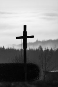 Graveyard cross in front of misty forests