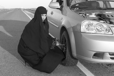 Portrait of woman in burka replacing tire on road