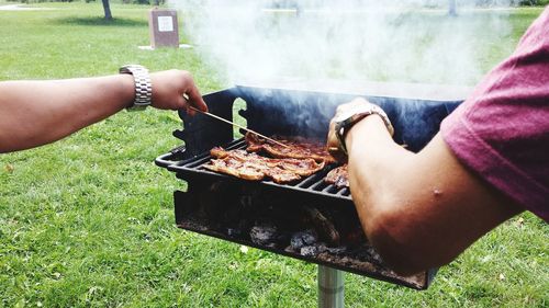 Cropped image of men barbecuing in park