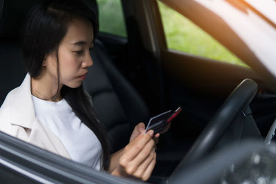 Young woman using mobile phone in car
