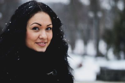 Close-up portrait of smiling young woman in snow