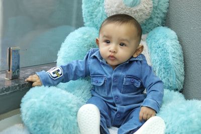 Cute baby boy sitting on toy at home