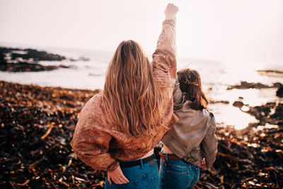 Rear view of couple standing at beach against sky