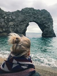 Rear view of woman against natural arch at beach