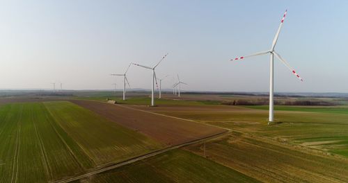 Windmills on field against clear sky