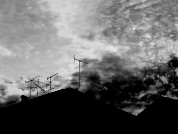 Low angle view of silhouette telephone pole against sky