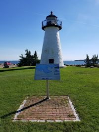 Lighthouse on field against sky