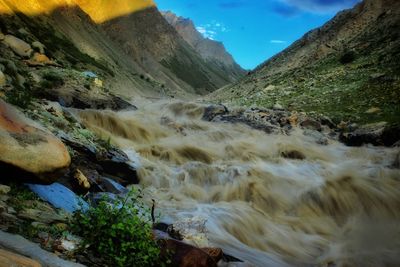 Scenic view of muddy river captured with a long exposure in a valley against sky