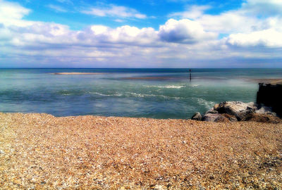 Scenic view of beach against cloudy sky