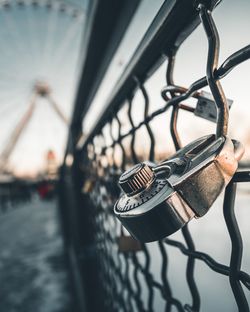 Close-up of padlock hanging on railing against sky