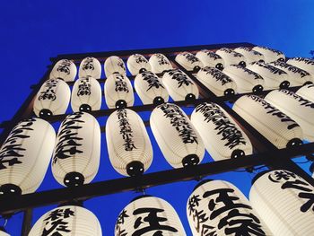 Low angle view of lanterns hanging against clear blue sky