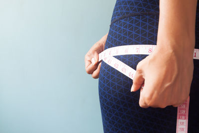 Midsection of woman holding hands against white background