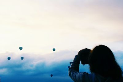 Rear view of woman photographing against sky