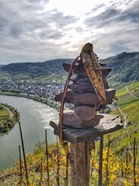 Close-up of wooden post by river against sky