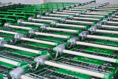 Many empty green shopping carts in row. row of parked trolleys in supermarket.