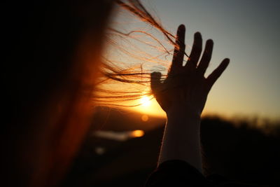 Close-up of silhouette hand against sky during sunset