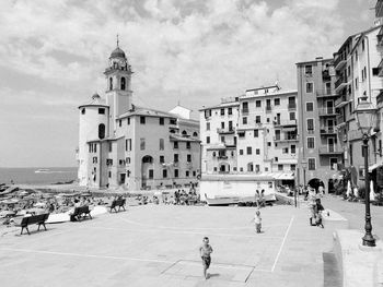 People on street by buildings against sky in city
