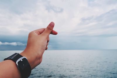 Cropped hand of man gesturing against sky