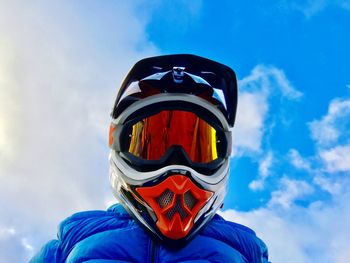 Low angle view of man in helmet against blue sky