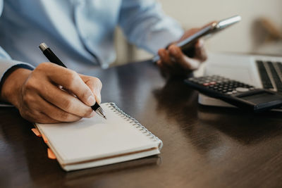 Midsection of man using mobile phone on table