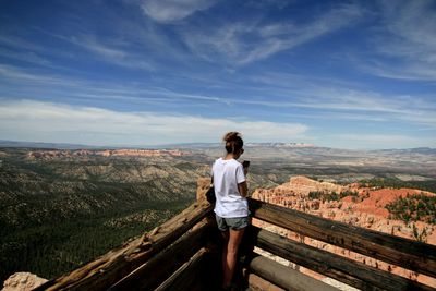 Rear view of woman looking at mountains against blue sky