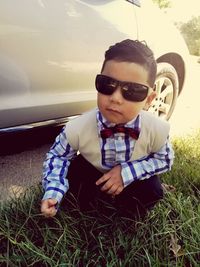 Boy wearing sunglasses on grass against sky