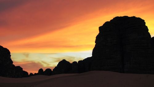 Silhouette rock formation against orange sky