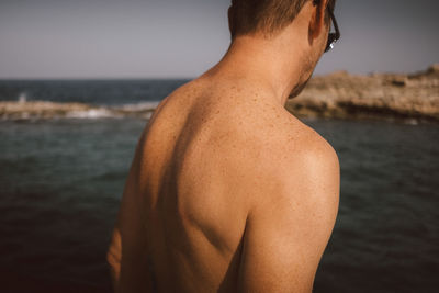 Rear view of shirtless man at beach on sunny day