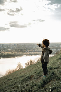 Rear view of woman walking on field against sky