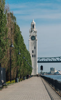 Clock tower amidst footpath against sky