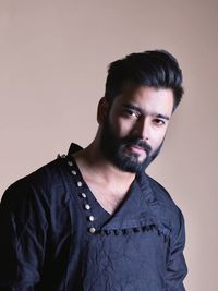 Portrait of young man standing against wall