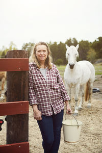 Portrait of female farmer leaning on fence in farm