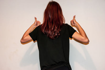 Rear view of woman standing against wall