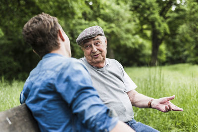 Portrait of senior man sitting on a bench talking to his grandson