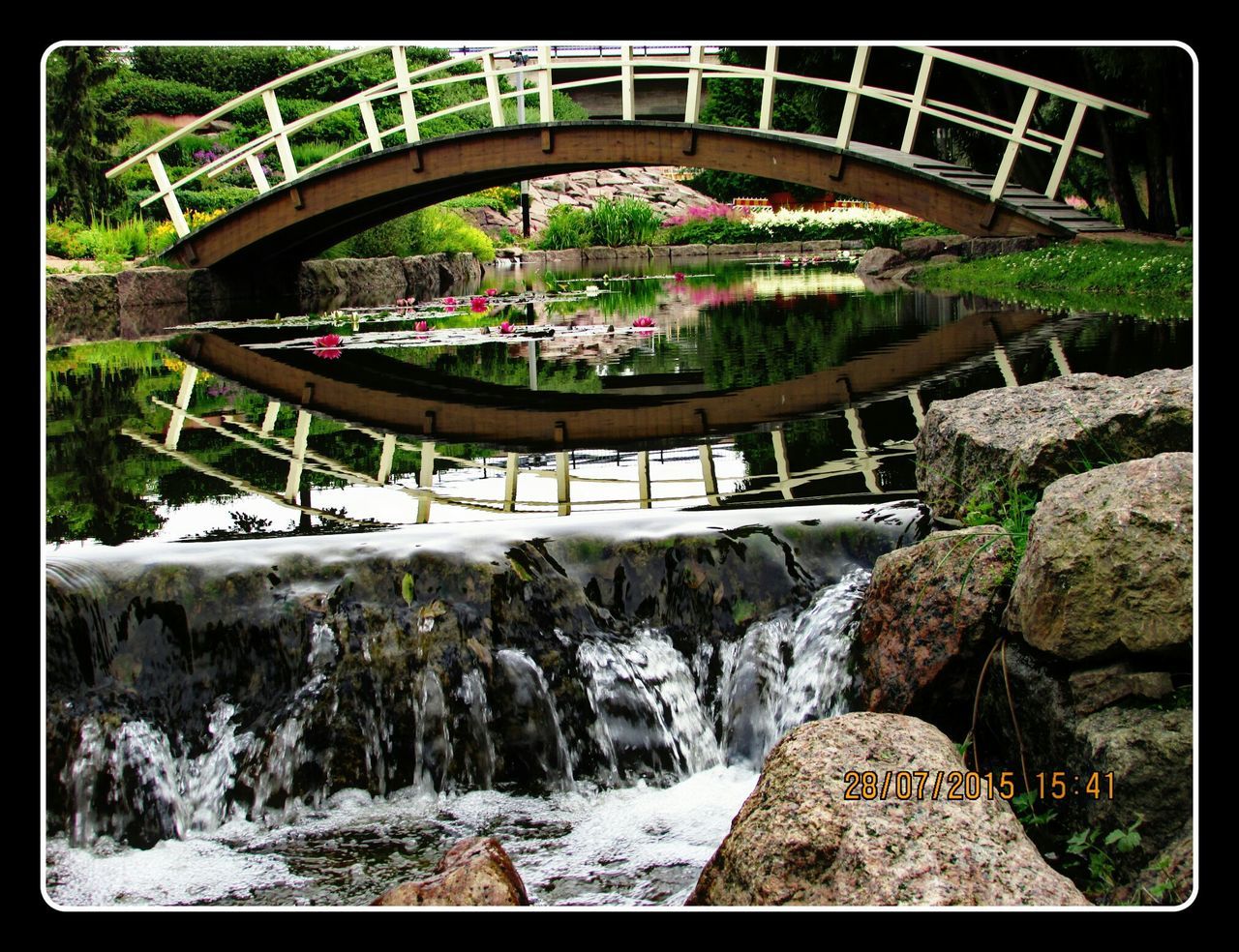 transfer print, tree, auto post production filter, water, built structure, architecture, bridge - man made structure, railing, plant, park - man made space, steps, nature, growth, connection, footbridge, day, beauty in nature, flowing water, fountain, outdoors