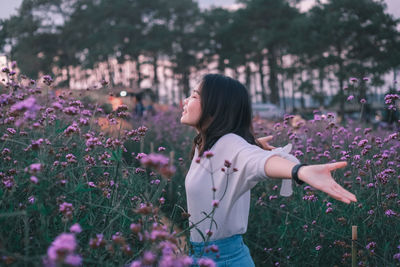 Rear view of woman standing by flowering plants on field