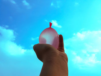 Low angle view of person hand against blue sky