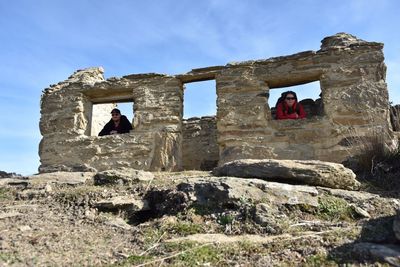 Low angle view of men on rock against sky