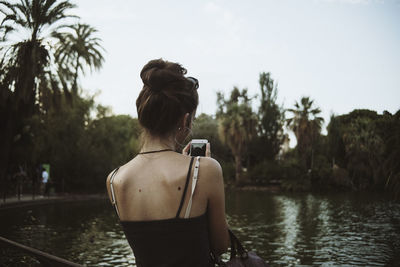 Rear view of woman photographing against sky