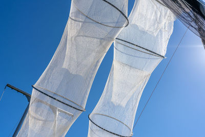 Low angle view of fishing net against clear blue sky