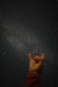 Low angle view of hands against sky at night