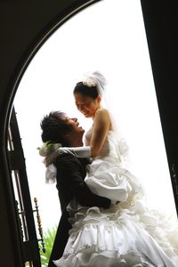 Low angle view of groom carrying bride seen through doorway