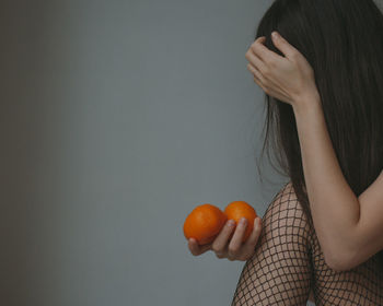 Sad woman in black lingerie ant fishnet tights with mandarins