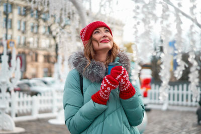 Beautiful smiling young woman wearing knit hat standing outdoors