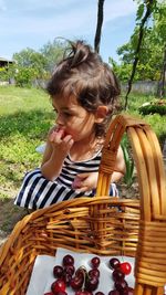 Girl looking away while sitting by basket