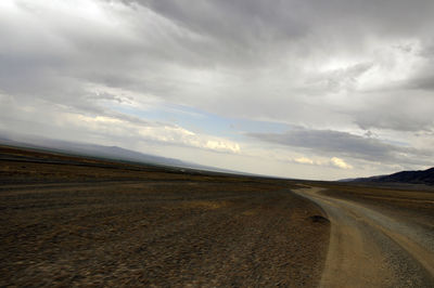 Road leading towards landscape against sky