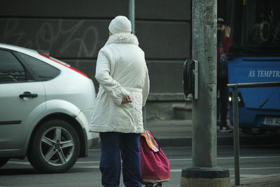 Rear view of man walking on street in city