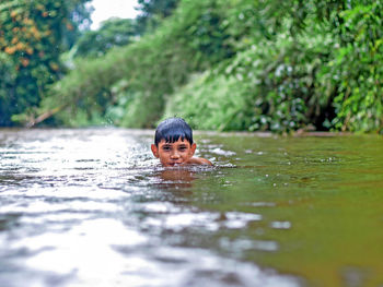 Close-up portrait of smiling girl swimming in water