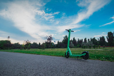 Empty park bench on field against sky