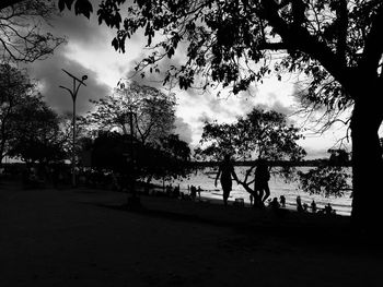 Silhouette people in park against sky